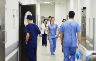 Busy nurses and doctors walking through corridor in hospital