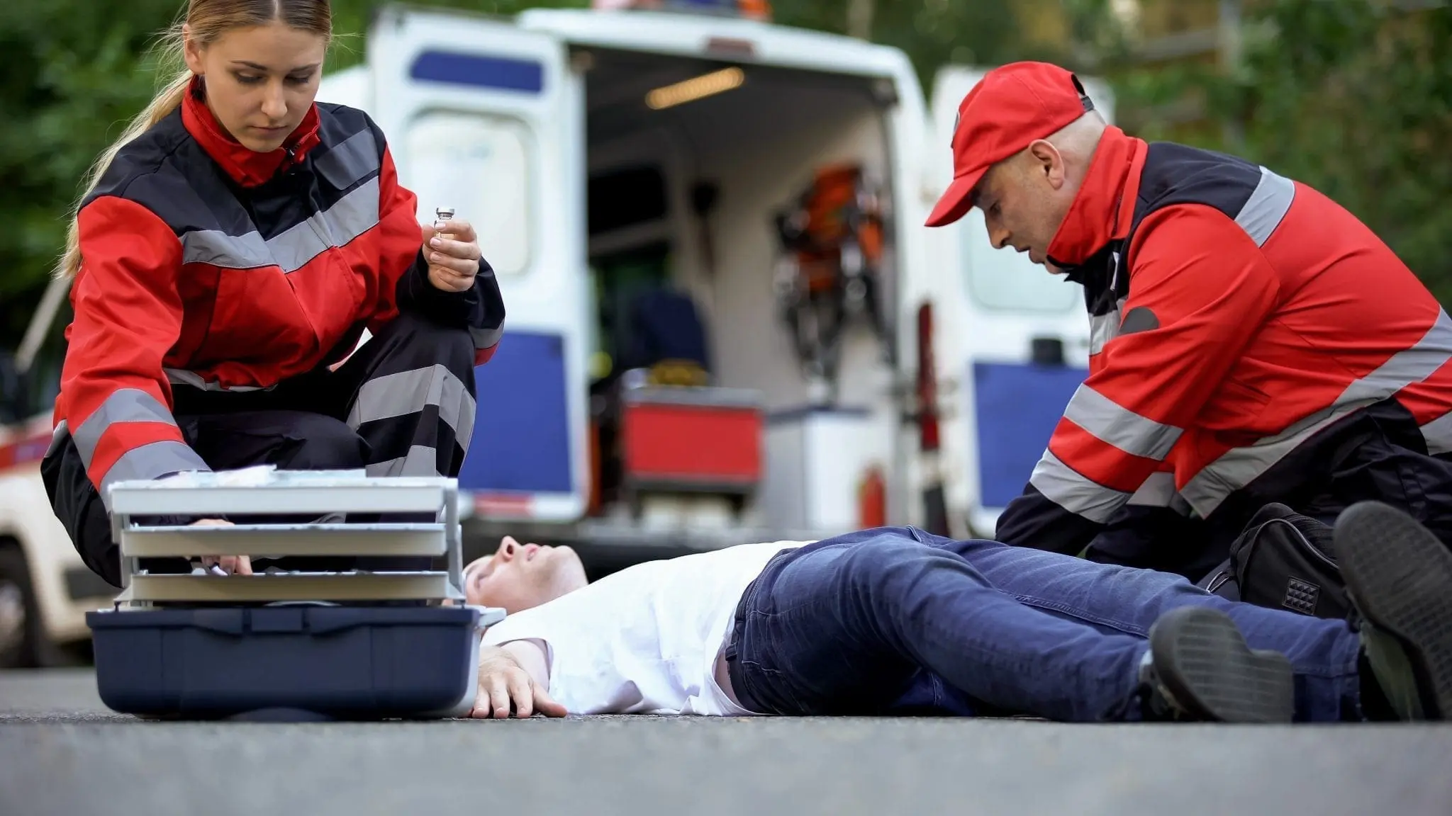 Medics helping man on road, preparing insulin to unconscious diabetic, first aid
